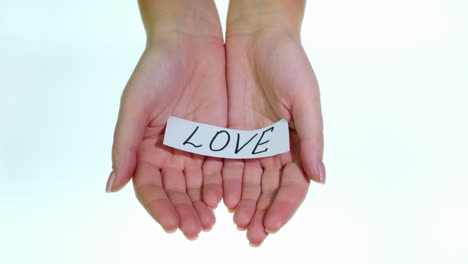 note love in female hands on a white background