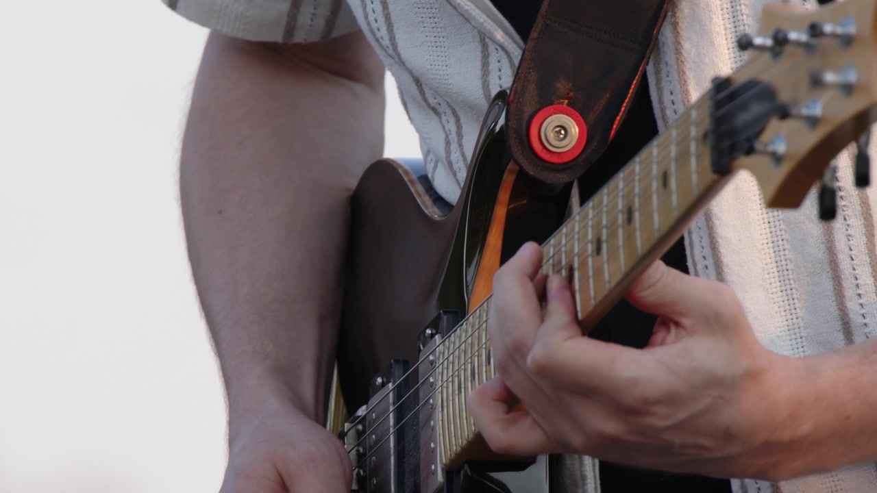 Yakın çekim tekniği: Beyaz gökyüzüne karşı elektro gitar çalan gitarist