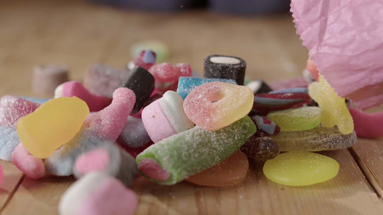 variedad de dulces coloridos azucarados arrojados de la bolsa sobre la mesa, slomo