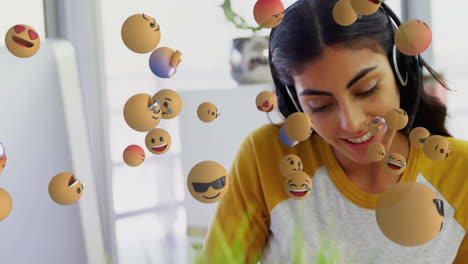 animation of biracial woman talking with headphone over multiple emojis passing by