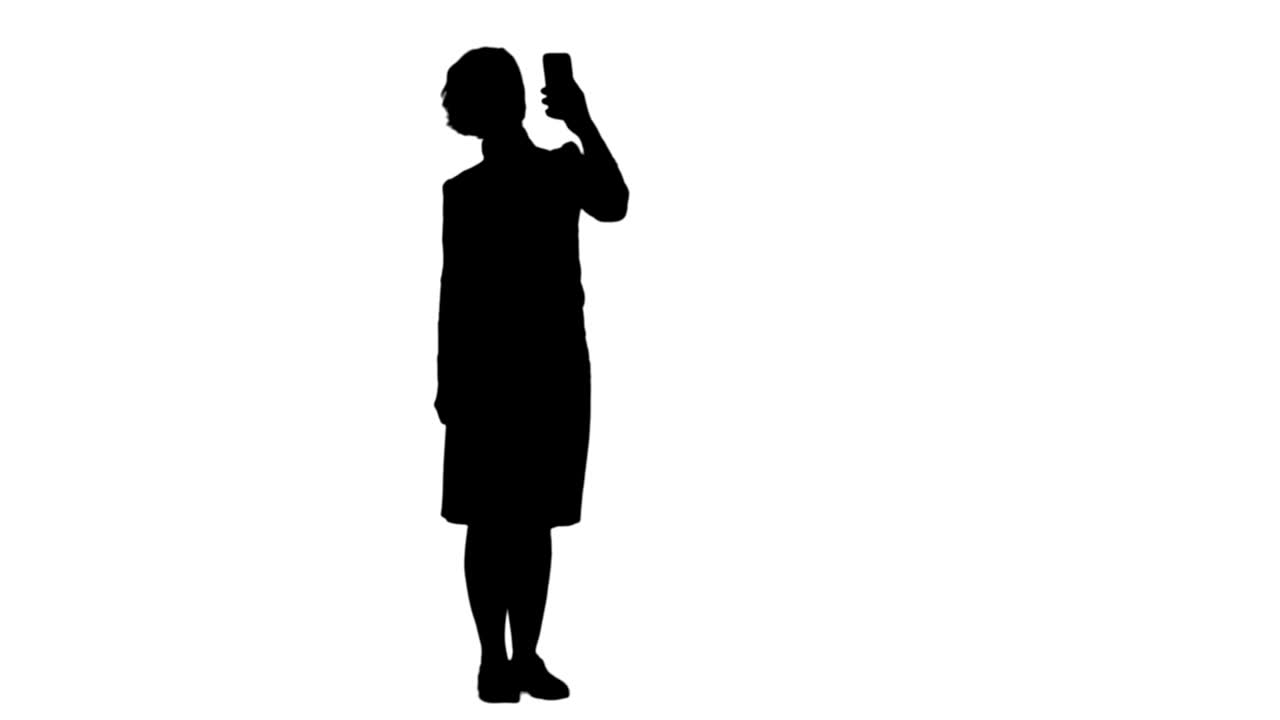 Silhouette Smiling cute woman making selfie photo on smartphone track matte