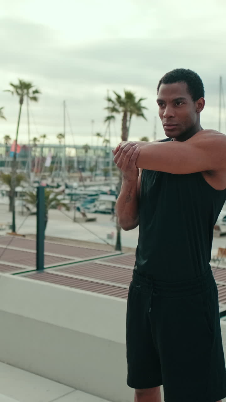 Giovane uomo che fa stretching vicino al porticciolo