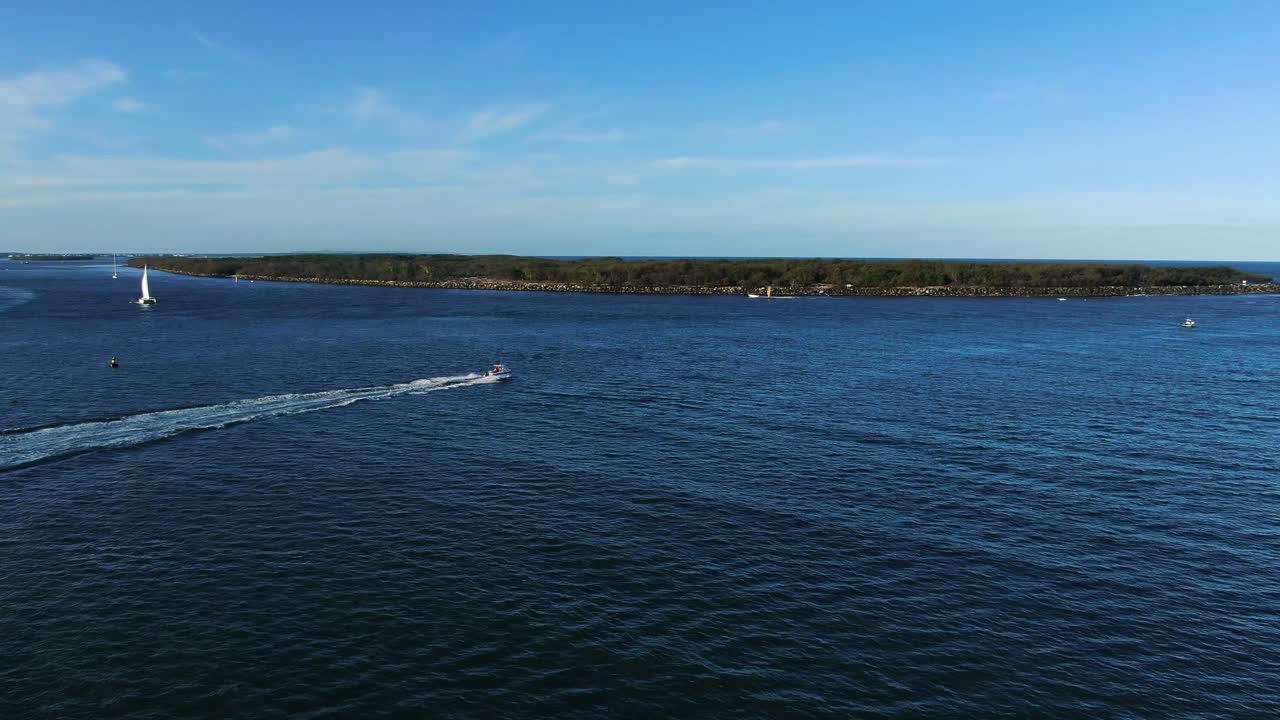 Speedboat leaving through Gold Coast seaway near Wave Break  island and Gold Coast spit, panning right 
at sunset