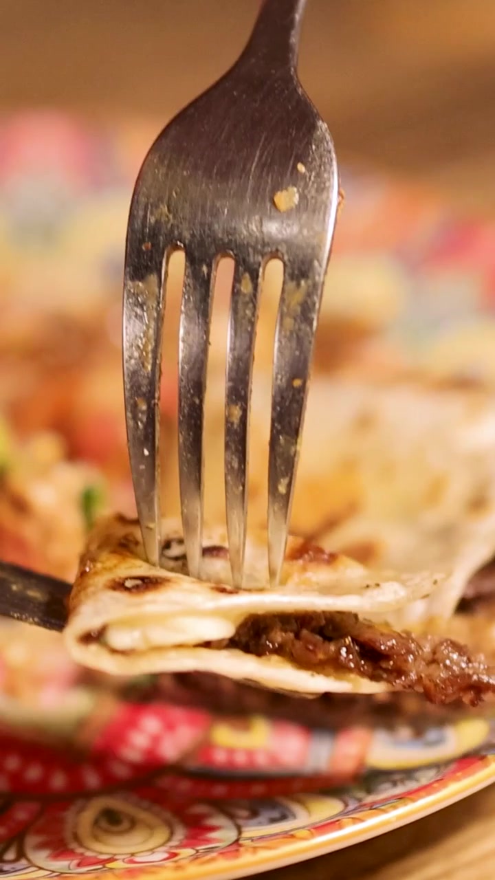Krájení a zvedání kousku hovězí quesadilly vidličkou a nožem