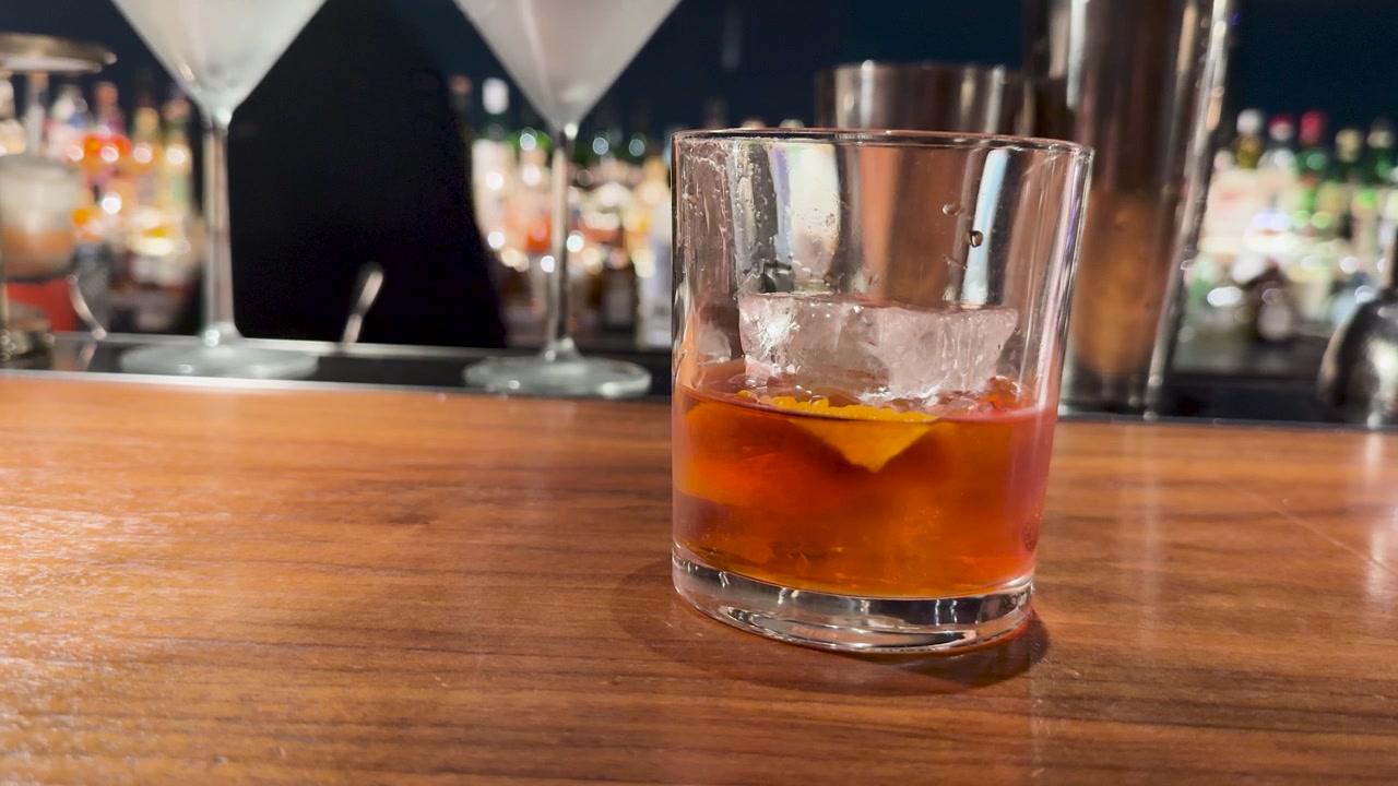 Primo piano di un cocktail ambrato con ghiaccio su un bancone di legno a Kanazawa