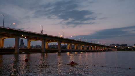 Nachtbeleuchtung-Und-Autoverkehr-Auf-Der-Banpo-Brücke-über-Den-Han-Fluss-Bei-Atemberaubendem-Sonnenuntergang,-Sonnenlichtreflexionen-Im-Wasser-–-Statische-Echtzeit