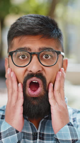 indian man looking surprised at camera shocked by sudden win good victory news wow in city street