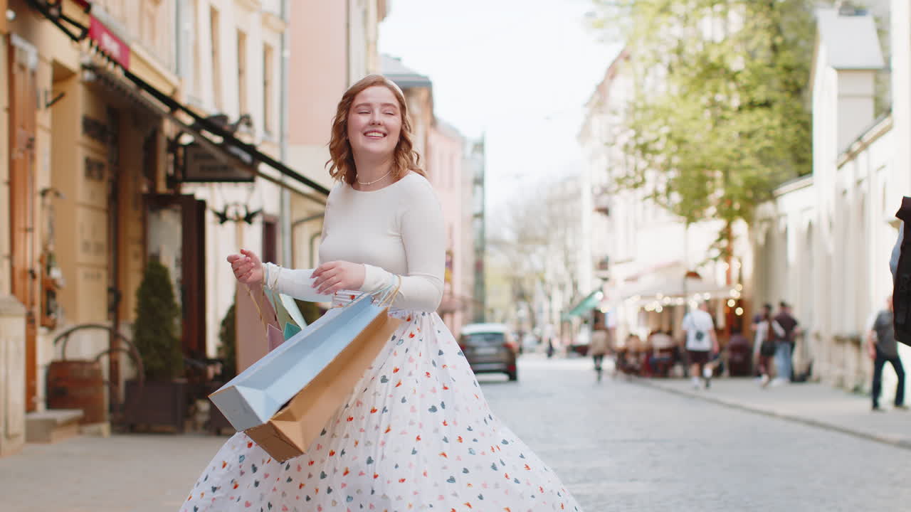 Happy young woman shopaholic consumer after shopping sale with full bags walking in city town street
