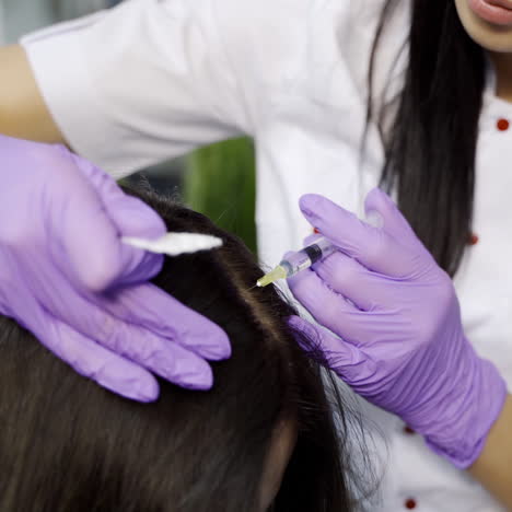 an experienced cosmetologist disinfects the skin of head with the using of a sponge and begins to doing a procedure of mesotherapy in the center of cosmetology. close-up.