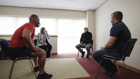 four people meeting maintaining social distance and wearing face masks