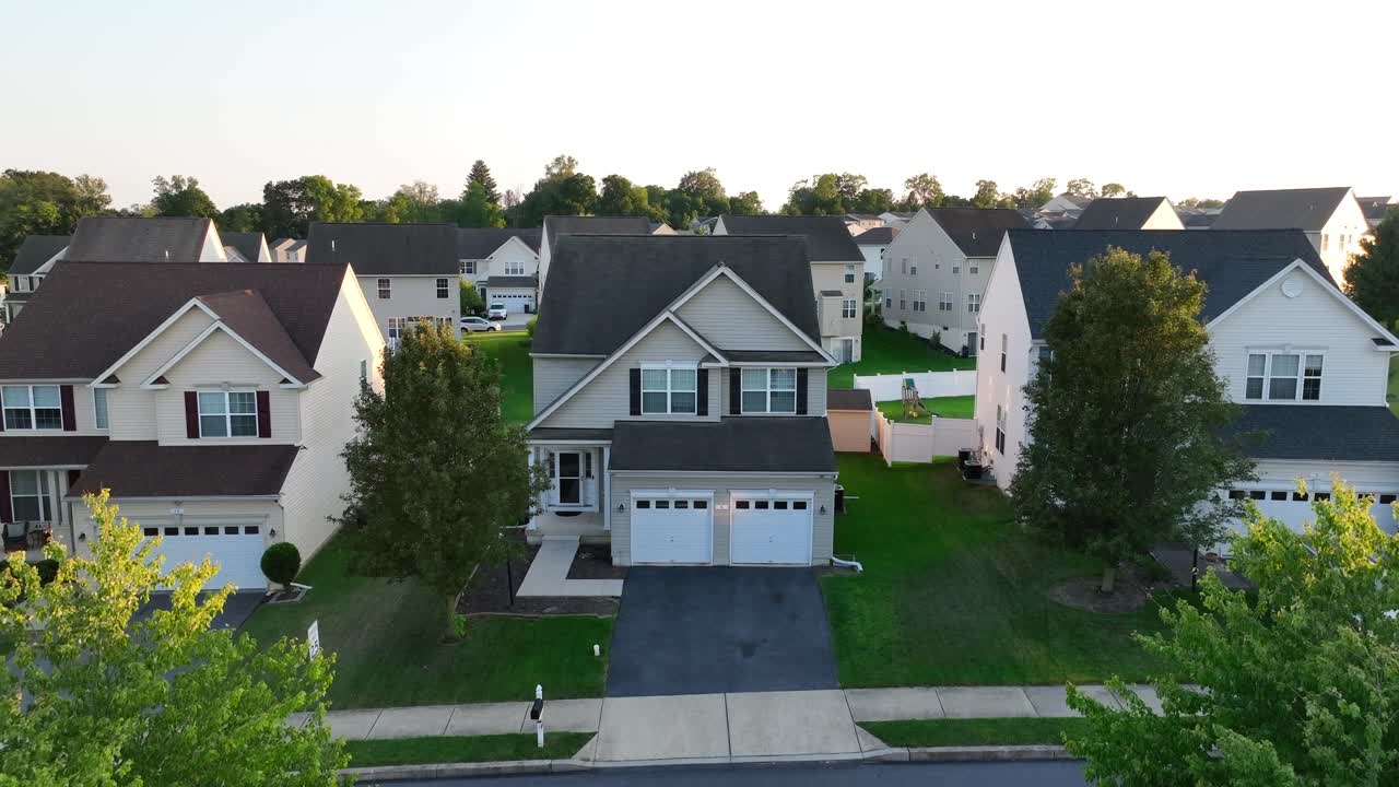 Suburban neighborhood with detached houses and green lawns during summer sunset