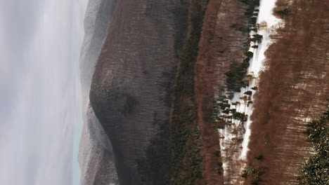 aerial push in towards forest and foothill dusted in fresh snow