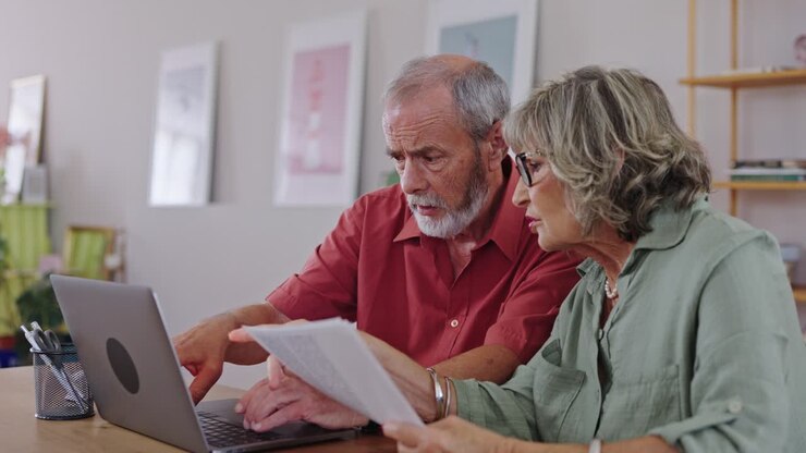 Senior couple managing finances at home with a laptop