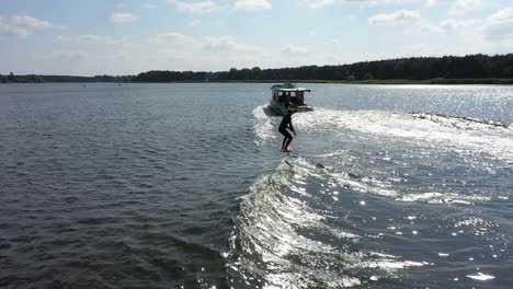 surfer on foil surfing waves behind boat