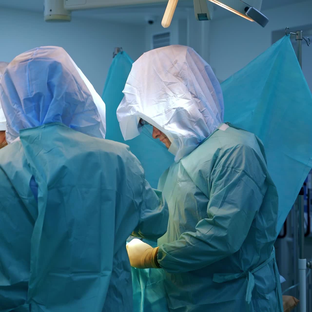 Healthcare professionals wearing protective medical suits stand around the patient. Surgeons perform trauma operation in the hospital