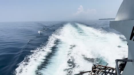 pov from the back of a speedboat looking at the wake being left as the motorboat sails along the water