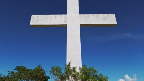 dolly pan up close up of a white christian cross in a cemetery against a blue skies in the philippines