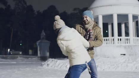 una pareja joven girando juntos en el hielo.