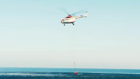 helicóptero volando después de llenar un balde de agua para volar al incendio forestal