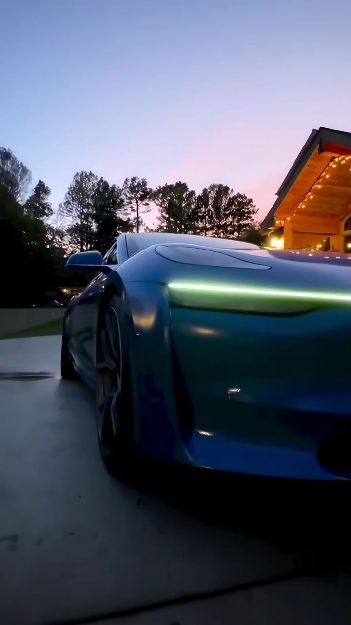 Elegante auto elettrica blu con fari a colore variabile al crepuscolo