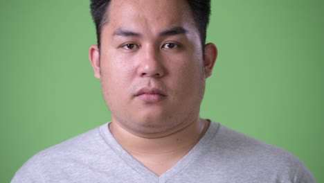 초록색 배경에 젊은 잘생긴 과체중 아시아인