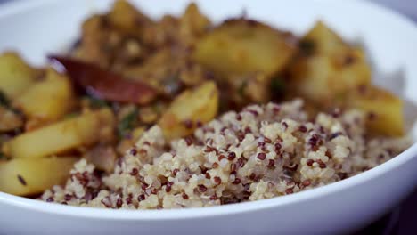 Primer-Plano-De-Curry-De-Papaya-Girando-En-Un-Recipiente-Blanco-Con-Quinua-Al-Lado