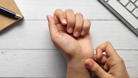 woman checking her pulse at her desk