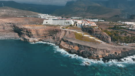 Aerial-view-in-orbit-over-the-coast-of-the-town-of-Agaete-and-spotting-a-large-hotel