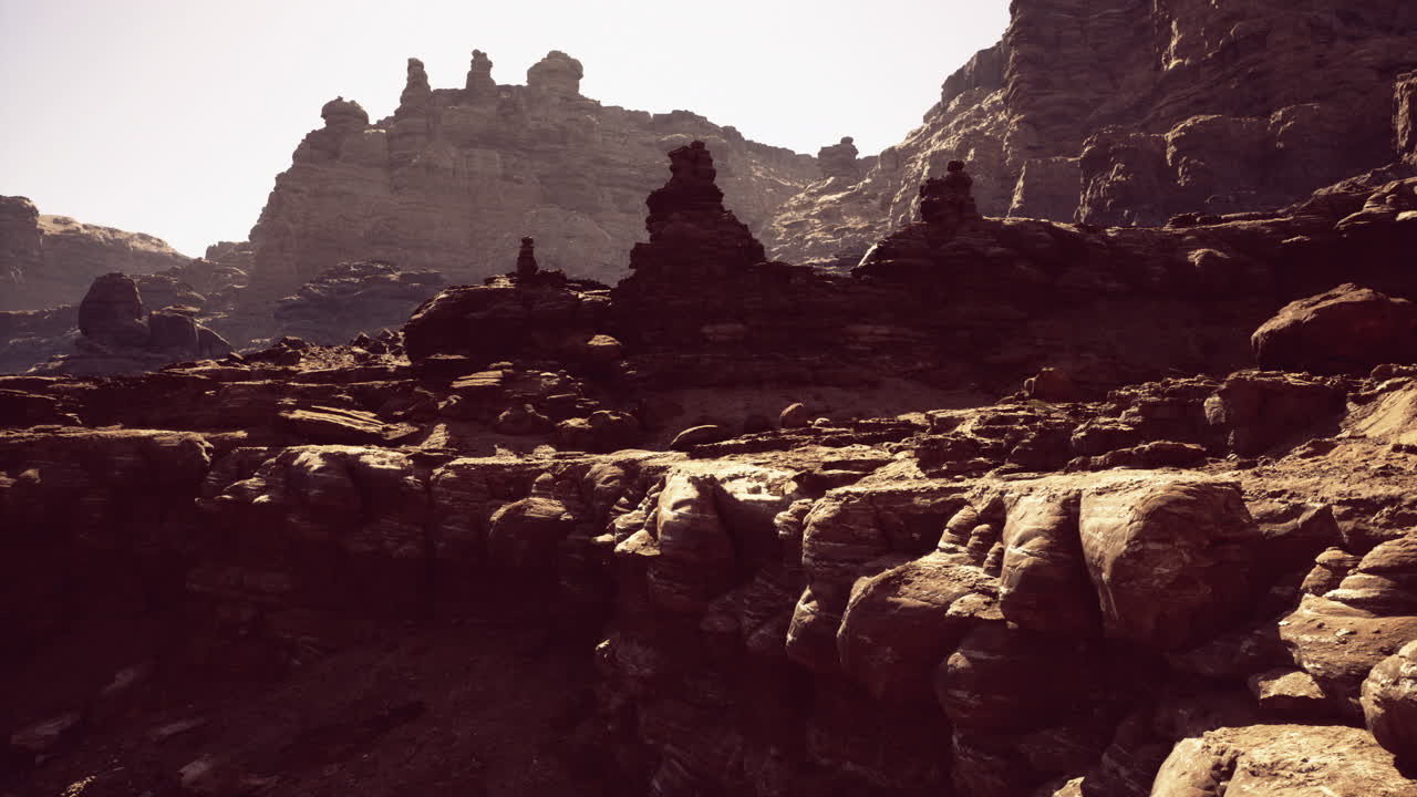 Rocky landscape with towering formations under bright sunlight near mountains