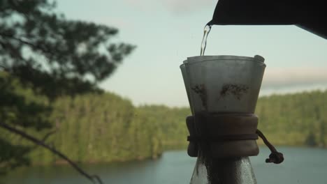 filling up natural organic paper coffee filter in glass chemex coffee brewing apparatus in canadian forest