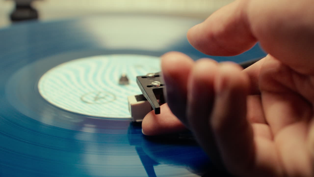 Primo piano di un disco vintage che sta finendo e una mano che ritira la puntina.