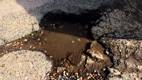 un agujero gigante en la carretera lleno de agua - el coche pasa por encima