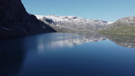 Lake-in-the-Rauma-Commune-of-Norway,-with-snow-capped-mountains-in-the-background