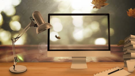 desktop computer and office equipment on a table against autumn maples leaves falling in background