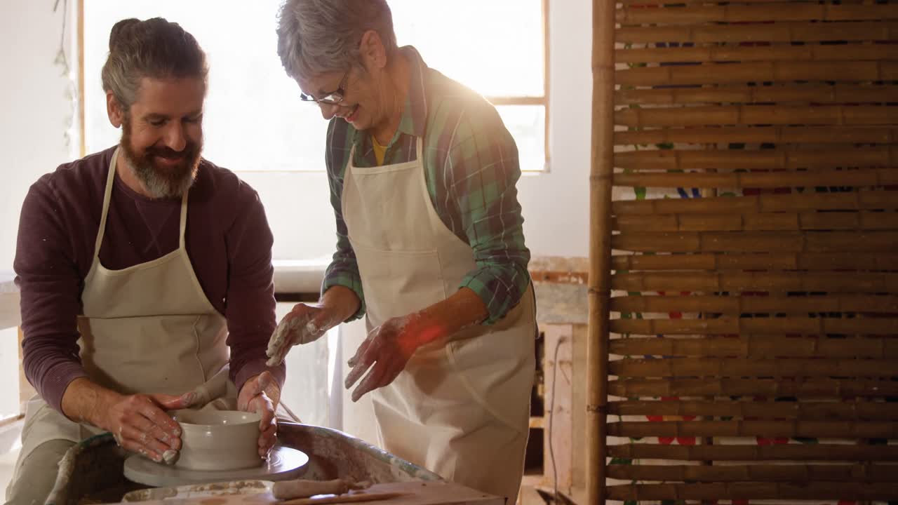 Male potter assisting female potter