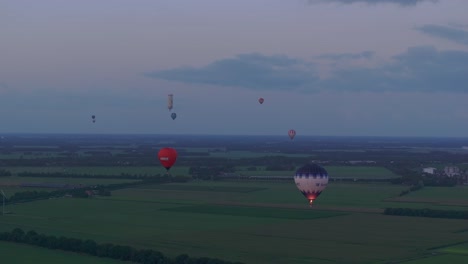 Aerial-view-of-Colorful-hot-air-balloons-epic-flying-above-meadow,-Netherlands