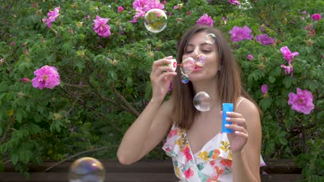 smiles young beautiful happy woman blowing bubble in the park with blossom rose