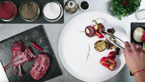 Chef-plating-a-big-piece-of-meat-with-some-vegetables-as-side-dish,-close-up-view-from-above