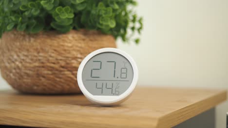 digital thermometer and hygrometer with potted plant on a wooden table