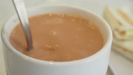 a cup of milk tea with a spoon and sandwich