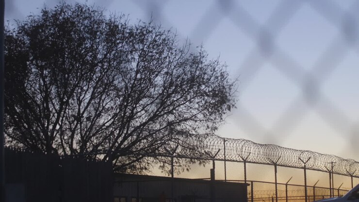 Prison Fence At Sunset Through Razor Wire