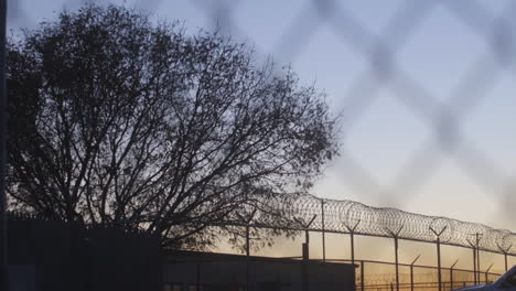 Gefängniszaun-Bei-Sonnenuntergang-Durch-Stacheldraht