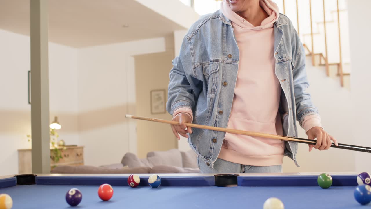 Entering room man picking cue stick blue-felt pool table aligning shot and striking billiard balls