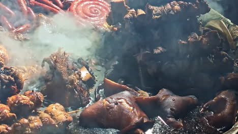 outdoor cooking of skewers and meat boiling in fire pit with smoke and flames under night sky