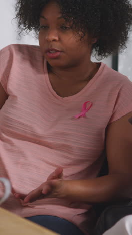 Vertical-Video-Of-Mid-Adult-Woman-Wearing-Pink-Breast-Cancer-Awareness-Ribbon-Meeting-And-Talking-At-Therapy-Support-Group-For-Cancer-Treatment-Patients-With-Counsellor