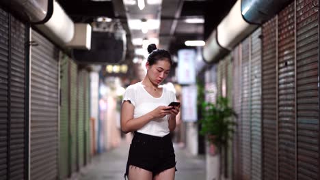 ethnic woman with smartphone walking on underground passage