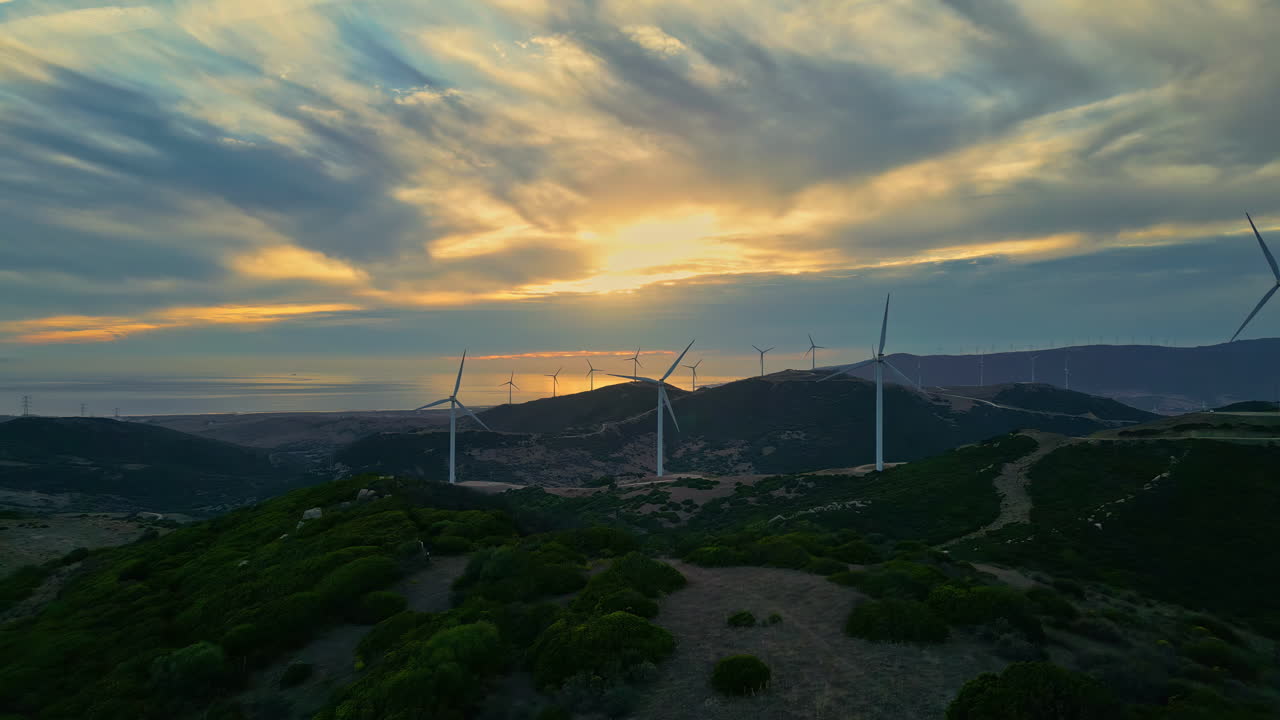 Aerogeradores circundando o Observatório Ornitológico El Cabrito ao pôr do sol em Cádis, Espanha