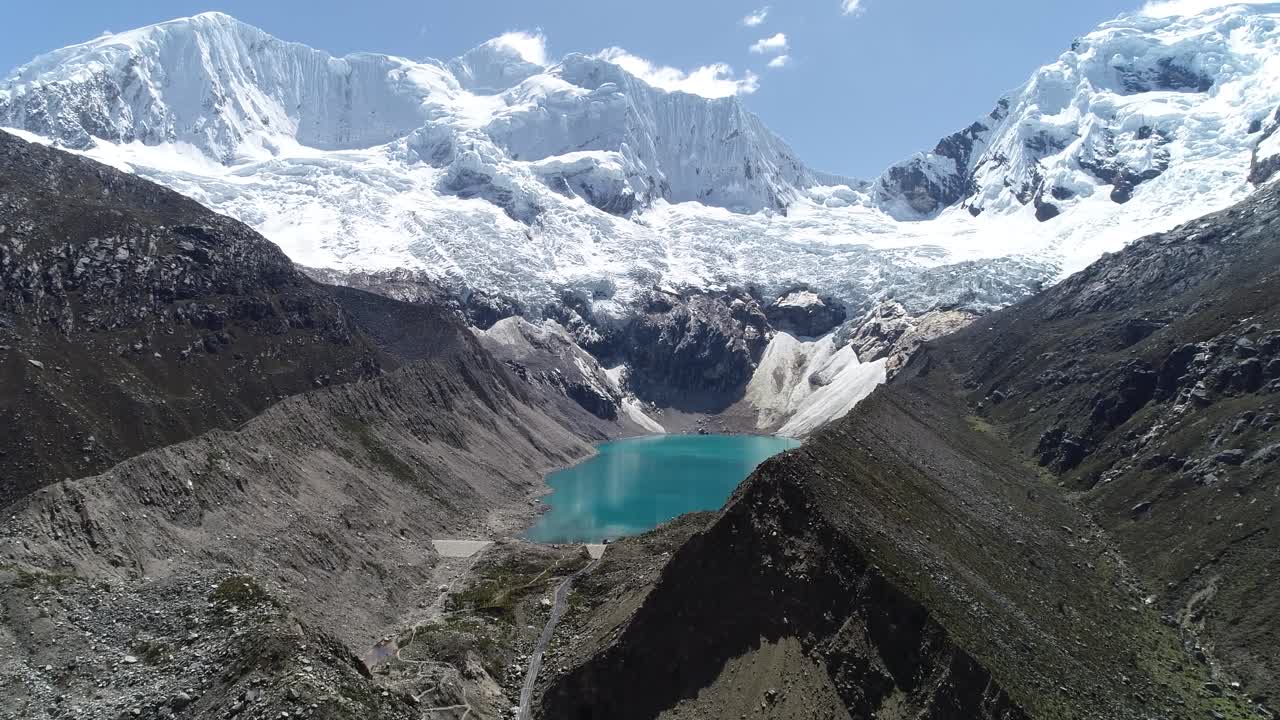 A stunning turquoise glacial lake sits between rugged Andean peaks, reflecting pristine snow and sky. Perfect for travel, nature, and environmental projects.
