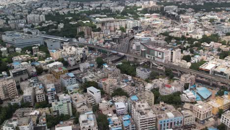 Luftaufnahmen-Einer-Stadt-In-Indien-Zeigen-Gebäude-Und-Bäume-Parallel-Zu-Eisenbahnschienen-Und-Eine-U-Bahn-Station-Mitten-In-Der-Stadt