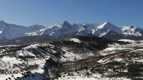 aerial cinematic drone mid winter of san juan mountain range ridgway telluride 14er stunning ranching farm land of colorado early morning mid winter blue sky scenic landscape to the left movement